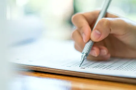 A dental consultant writing notes during a practice assessment